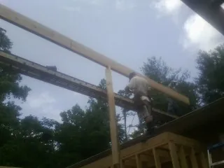 Carpenter setting a ridge beam over a new addition frame — Ice Dam Removal by Roofing Brothers in Holcomb
