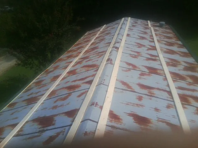 Rusted metal roof panels with new wood purlins before replacement — Storm Damage Roof Repair in Holcomb by Roofing Brothers