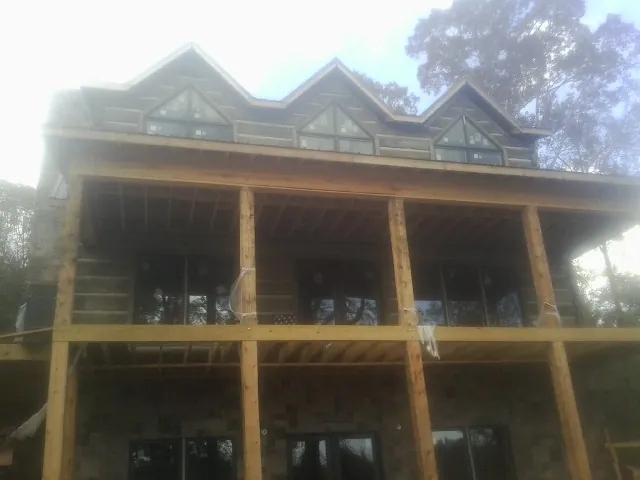 Dormers and porch framing on a large log home under construction — Roof Coating work by our crew in Holcomb