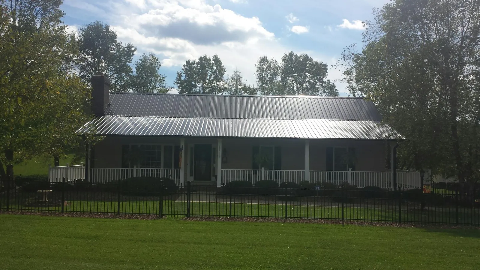 Gray metal roof on a brick ranch with a full width front porch — Gutter Guard Installation work by our crew in Holcomb