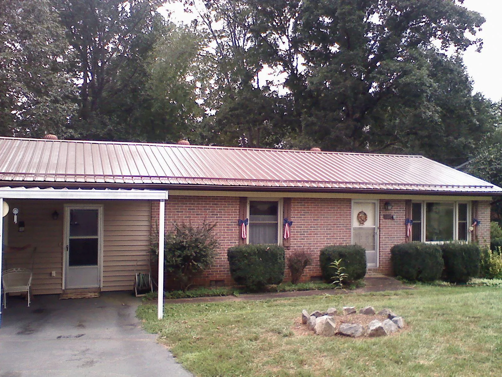 Bronze metal roof and carport on a brick ranch home — Roof Repair work by our crew in Holcomb